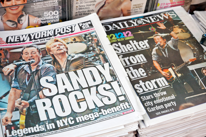 "New York City, USA - December 13, 2012: New York Post and Daily News in a newsstand on the street with headlines on the front pages reporting the 121212 Concert for Hurricane Sandy Victims in the sold-out Madison Square Garden. Bruce Springsteen and Jon Bon Jovi can be seen."